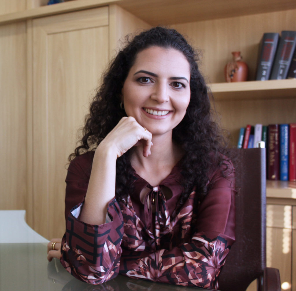 imagem da Dra Caroline Maroso em seu consultório, sorrindo